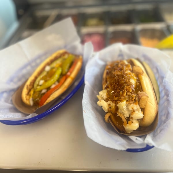 Two Hi Five Hotdogs, one with peppers and the other with mac and cheese and crispy onions.