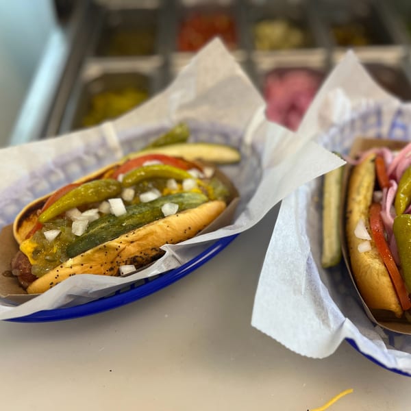 Two Hi Five Hotdogs, one with relish, onions, and peppers, the other with pickled onions.